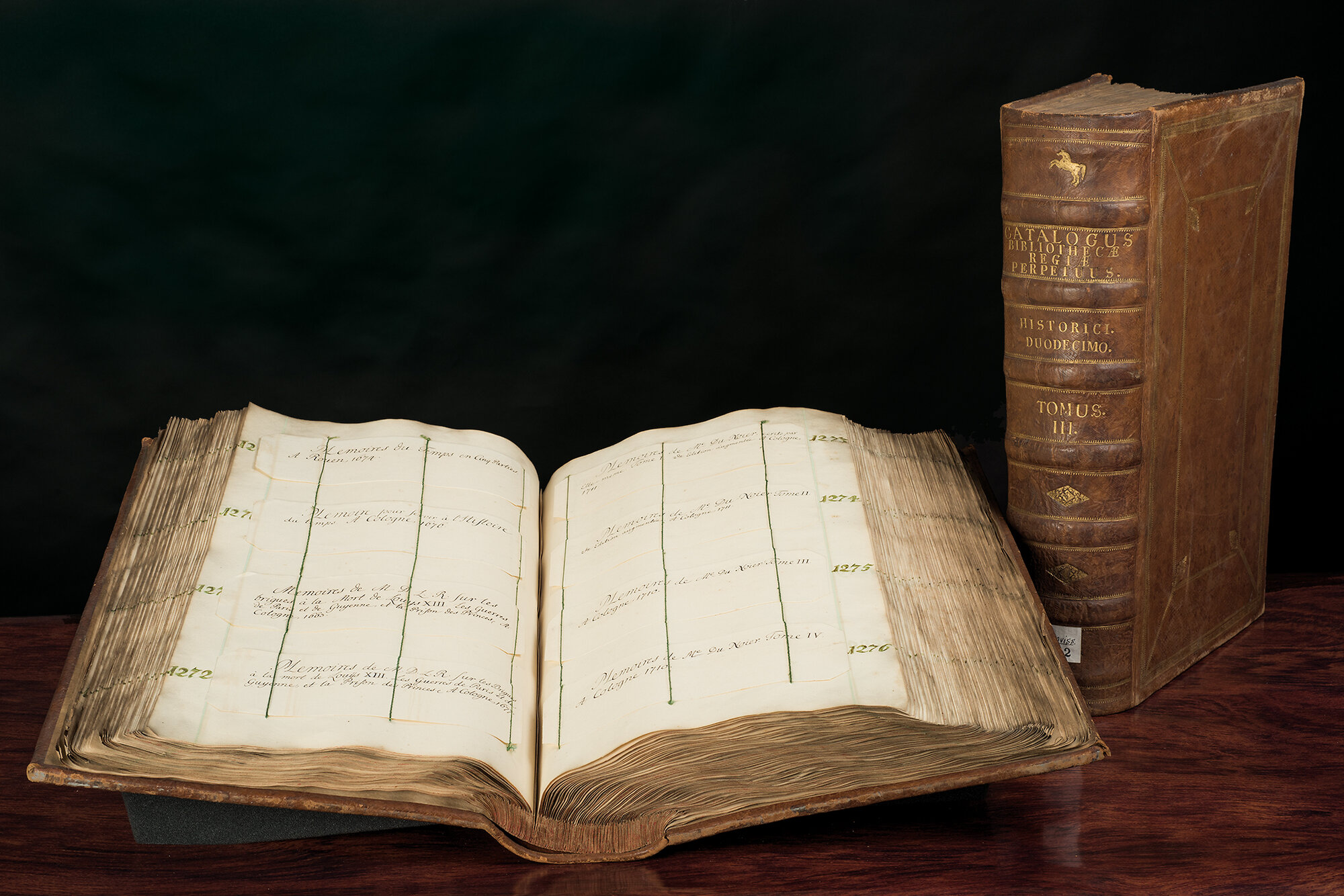 Catalogus perpetuum bibliotheca regiae © GWLB/Wollenberg Aufgeschlagener Catalogus perpetuum bibliotheca regiae mit Buch im Hintergrund