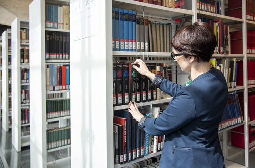 Eine Frau steht am Bücherregal